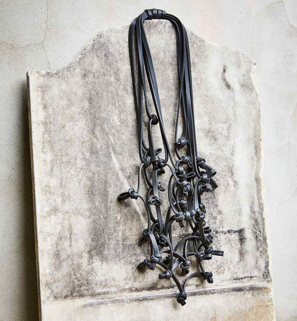 black knotted rubber necklace long black rubber necklace on a stone backdrop